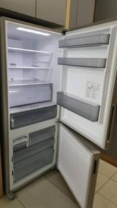 an empty refrigerator with its door open in a kitchen at Conezion 3-bedroom condo @ IOI City Mall Putrajaya in Serdang
