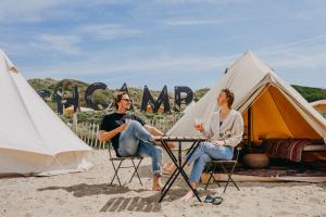a man and woman sitting at a table in front of a tent at Beachcamp Bloemendaal Surf Resort in Overveen
