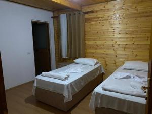 2 camas en una habitación con paredes de madera en Bujtina Vellezerit Grrela, en Theth