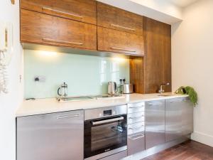 a kitchen with stainless steel appliances and wooden cabinets at Pass the Keys - Top Floor Flat in the heart of Portobello Market, London in London