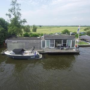 a house on a dock with a boat on the water at Luxe woonboot unieke locatie Friesland Âlde Feanen in De Veenhoop