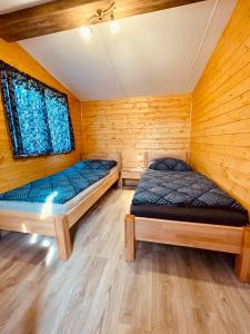 2 łóżka w pokoju z drewnianymi ścianami w obiekcie Domčeky na Ranči w mieście Sučany