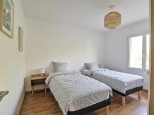 Duas camas num quarto com paredes brancas e pisos em madeira em Gîte de Kerninon Maison spacieuse et lumineuse em Ploulech