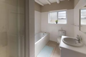 a white bathroom with a tub and a sink at Oyster Catcher in Cape St Francis +13 photos