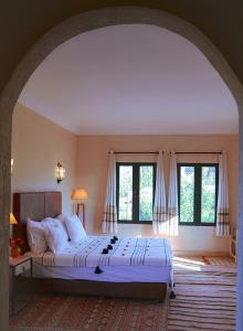 een slaapkamer met een groot bed in een kamer met ramen bij Villa Atlas Secret in Ourika