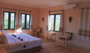 a bedroom with a bed and two chairs and windows at Villa Atlas Secret in Ourika