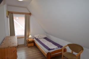 a small bedroom with a bed and a chair at Dom Gościnny Alba in Międzywodzie