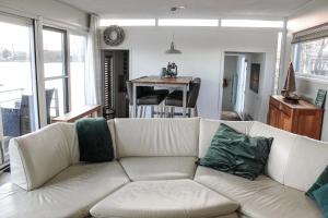 a living room with a white couch with green pillows at Luxe woonboot unieke locatie Friesland Âlde Feanen in De Veenhoop +13 photos