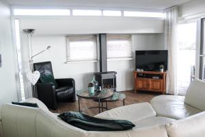 a living room with a white couch and a television at Luxe woonboot unieke locatie Friesland Âlde Feanen in De Veenhoop