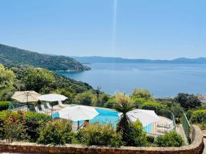 a swimming pool with umbrellas and a view of the water at Residence Roc E Mare Cargèse in Cargèse