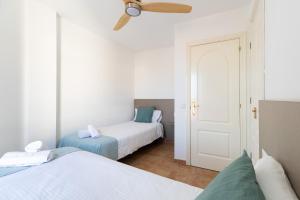 sypialnia z 2 łóżkami i wentylatorem sufitowym w obiekcie UpTown Urban Apartments w Corralejo