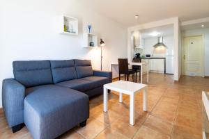 ein Wohnzimmer mit einem blauen Sofa und einem Tisch in der Unterkunft UpTown Urban Apartments in Corralejo