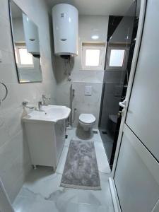 a white bathroom with a sink and a toilet at Ceka Apartments in Ulcinj