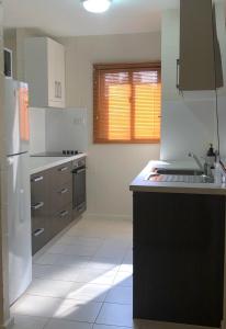 a white kitchen with a sink and a stove at Hedland Accommodation in Port Hedland