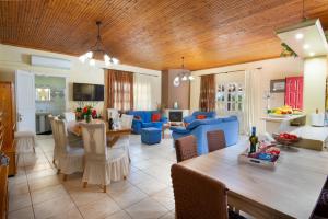 a kitchen and living room with a dining table and blue chairs at Romanatika Villa Paxos by Dandelion Villas in Gaios