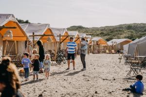 a group of people on a beach with tents at Beachcamp Bloemendaal Surf Resort in Overveen