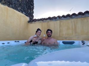 un hombre y una mujer sentados en una bañera con bebidas en Locanda Il Cortile, en Vignale
