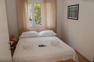 Un dormitorio con una cama blanca con toallas y una ventana en Apartmani Rafaela, en Orebić