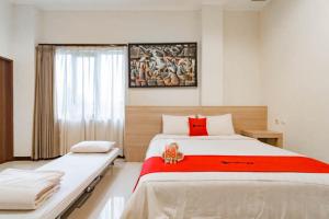 a bedroom with two beds and a red blanket at RedDoorz near Lembang Park & Zoo 2 in Lembang