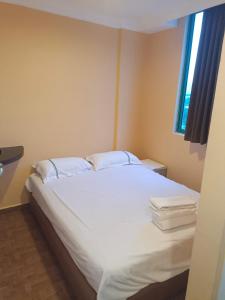 een slaapkamer met een bed met witte lakens en een raam bij Hotel Duke in Singapore