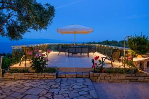 a patio with a table and an umbrella at Romanatika Villa Paxos by Dandelion Villas in Gaios