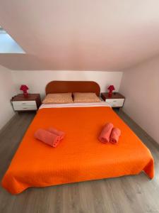 una camera con letto arancione e 2 pantofole rosa di Apartmani Velnic a Baška