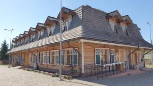 ein großes Holzgebäude mit einem Gameradach in der Unterkunft Hotelik ze śniadaniami "KUR" Myszyniec-Kurpie in Myszyniec