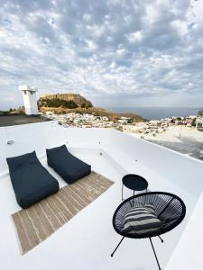 a balcony with a chair and a view of the ocean at ARTE LINDOS SUITES in Lindos