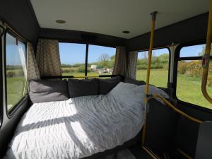 a bed in the inside of a bus with windows at Dawel Nos Glamping in Sarnau +13 photos