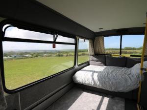 a bed in the back of a camper van with windows at Dawel Nos Glamping in Sarnau