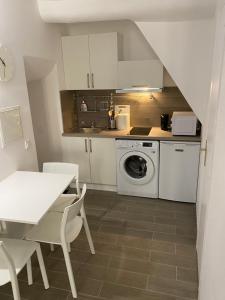 a kitchen with a washing machine and a table at Renovated studio in the heart of the Old Town in Menton