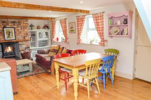 a kitchen and living room with a wooden table and chairs at Cob Cottage in Tomhaggard