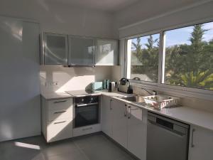 a kitchen with white cabinets and a large window at The Anemoni 5 Villa in Protaras