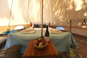 a bottle of wine and a bowl of fruit on a bed at Happy Glamping in Kalamaki Heraklion