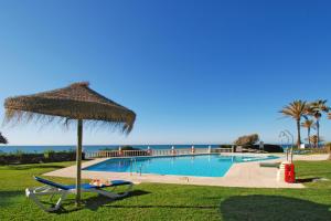 a person laying on a chair under an umbrella next to a swimming pool at Casa Linda La Lubina, front the beach La Lucera, Riviera del Sol in Sitio de Calahonda