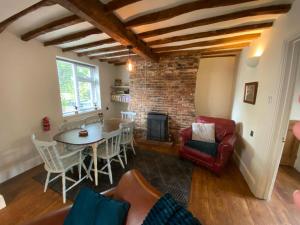 a living room with a table and a fireplace at Stoop Cottage - in the heart of Quorn in Quorndon