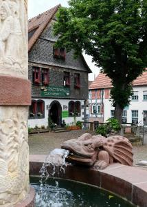 una fuente frente a un edificio con una estatua en Burgmannenhaus, en Steinau an der Straße