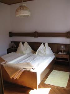 Elle comprend un grand lit avec des draps et des oreillers blancs. dans l'établissement Gasthof Laggner, à Steindorf am Ossiacher See