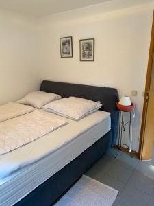 ein Bett mit zwei Kissen und einem Beistelltisch in einem Zimmer in der Unterkunft Ferienwohnung Hochfelln in Prien am Chiemsee