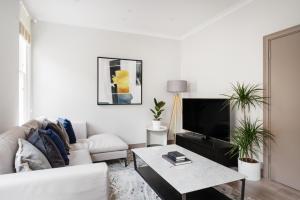 uma sala de estar com um sofá branco e uma televisão em Cosy Two Bedroom Apartment in Holborn em Londres