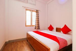 a bedroom with a bed with red pillows and a window at Super OYO New Suhani House in Rāmnagar