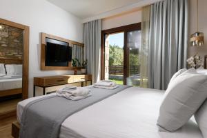 a bedroom with a bed and a tv and a window at La Terra Petra in Skala Rachoniou