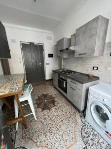 a kitchen with a stove and a table and a washing machine at Grey house in Genoa
