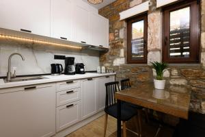 a kitchen with white cabinets and a stone wall at La Terra Petra in Skala Rachoniou