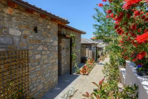 a stone house with a garden with red flowers at La Terra Petra in Skala Rachoniou