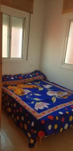 アシラにあるAppartement 3 éme étage dans la médina Kédimaのカラフルな掛け布団付きのベッド1台