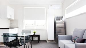 a kitchen with a glass table and a refrigerator at Excelsior Apartments at Glebe in Sydney