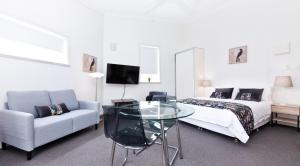 a bedroom with a bed and a glass table and a couch at Excelsior Apartments at Glebe in Sydney