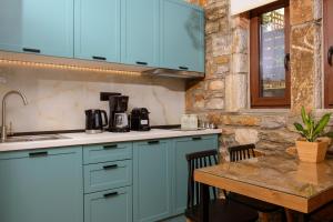 a kitchen with blue cabinets and a small table at La Terra Petra in Skala Rachoniou