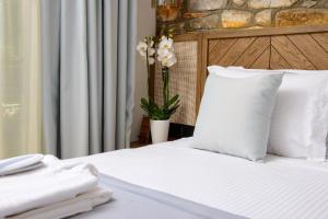 a white bed with white pillows and a vase with flowers at La Terra Petra in Skala Rachoniou